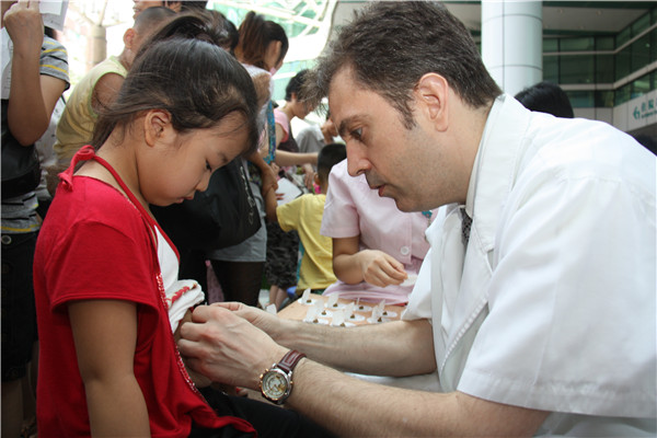 Paul Ryan, a US doctor studying traditional Chinese medicine in Guangzhou, capital of Guangdong province, treats a girl with sanfutie plaster, in July, 2012. [Photo provided to China Daily]