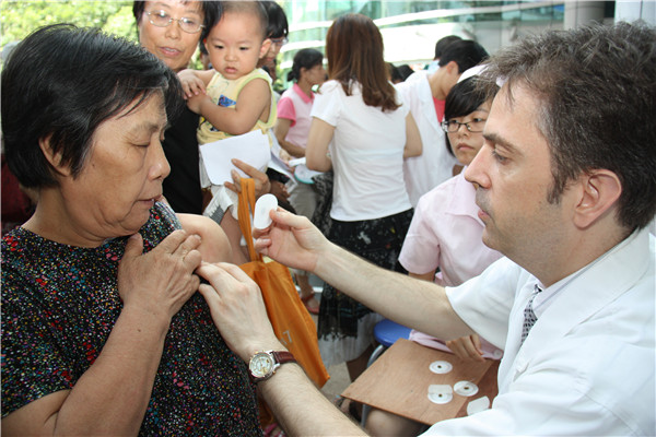 Paul Ryan treats a woman with sanfutie plaster, in July, 2012. [Photo provided to China Daily]