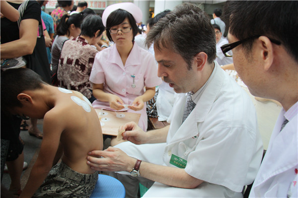 Paul Ryan treats a boy with sanfutie plaster, in July, 2012. [Photo provided to China Daily]