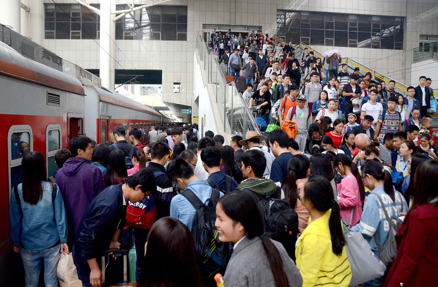 Passengers queue to board their train at the railway station of Zhengzhou, capital of central China's Henan Province, Oct. 7, 2015. A travel peak is seen around China on Wednesday, the last day of the seven-day National Day holidays. [Xinhua]