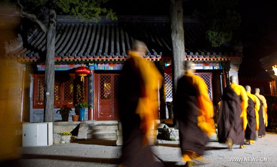 Monks attending Mid-Autumn Festival prayers walk past temple buildings in Longquan Monastery in Beijing, capital of China, Sept. 26, 2015. [Xinhua]