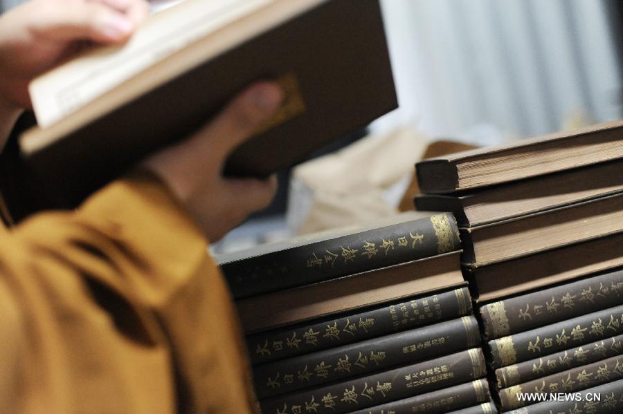 A monk scans books at the library in Longquan Monastery in Beijing, capital of China, Sept. 21, 2015. [Xinhua]