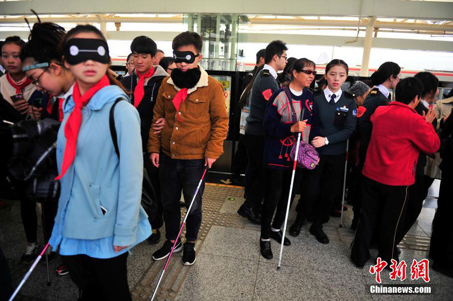 Ten blind people, accompanied by volunteers, wait to take the subway for the first time at a subway platform in Kunming, the capital of southwest China's Yunnan province on October 15, 2015. College students also cover their eyes with eye patches in a bid to understand the challenges faced by blind people when navigating the city's public transportation system. These are part of the activities to mark the International Blind Day. [Chinanews.com]