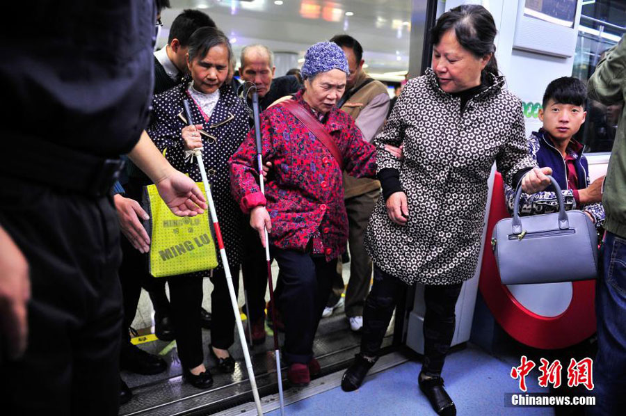 Blind people, accompanied by volunteers, take a subway train for the first time in Kunming, the capital of southwest China's Yunnan province on October 15, 2015. This is part of the activities to mark the International Blind Day. [Chinanews.com]