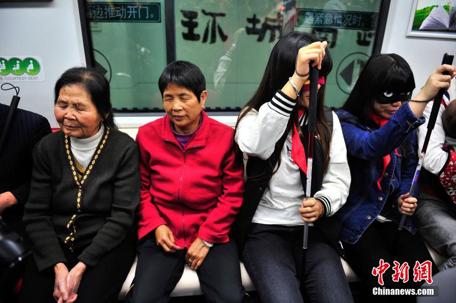 Two blind people, accompanied by volunteers, take a subway train for the first time in Kunming, the capital of southwest China's Yunnan province on October 15, 2015. Colleges students, also covers their eyes with eye patches in a bid to understand the challenges faced by blind people when navigating the city's public transportation system. These are part of the activities to mark the International Blind Day. [Chinanews.com]