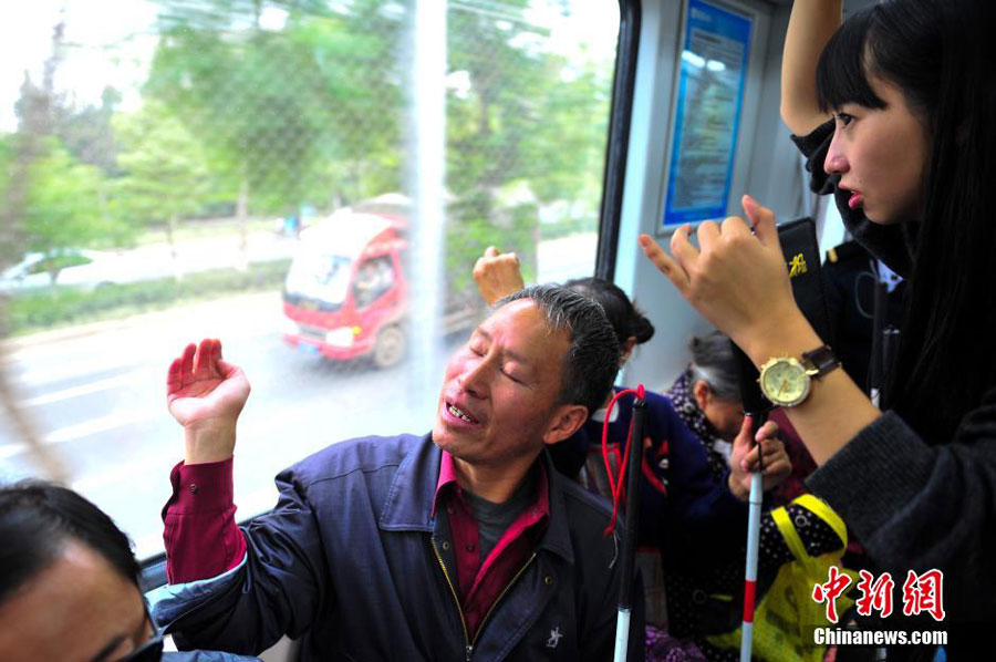 A blind person listens to the description of the surrounding landscape given by a volunteer as they take a subway train together. 10 blind people, accompanied by volunteers took the subway in Kunming, the capital of southwest China's Yunnan province on October 15, 2015. This is part of the activities to mark the International Blind Day. [Chinanews.com]