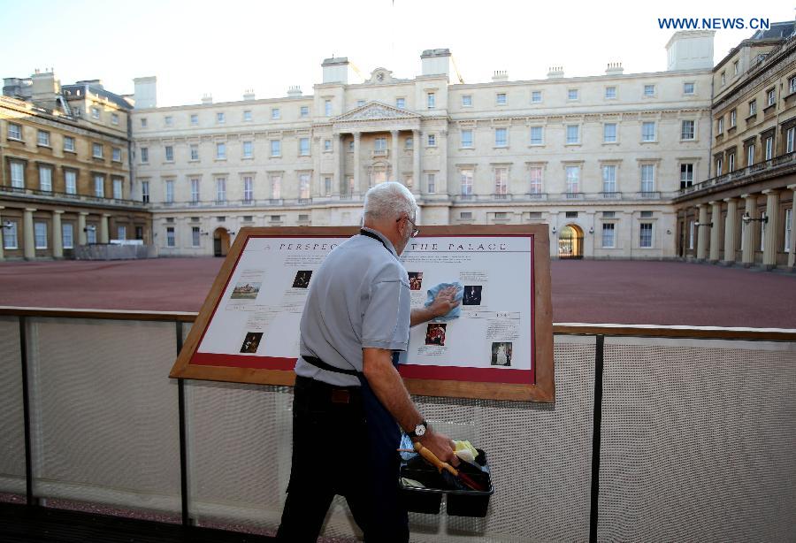 Photo taken on Sept. 7, 2015 shows a staff member cleaning a billboard at the Buckingham Palace in London, capital of Britain. The Buckingham Palace has served as the official London residence of Britain's sovereigns since 1837 and today is the administrative headquarters of the Monarch. [Xinhua]