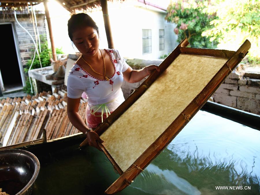 Ai Ying works at her family's paper-making workshop in Mangtuan Village of Gengma Dai and Wa Autonomous County, southwest China's Yunnan Province, Oct. 15, 2015. The time-honored Dai people's paper-making skill, with a history of several centuries, is mainly mastered by local women and was listed as a national intangible cultural heritage in 2006. Local villagers see it as a key money spinner. [Xinhua]