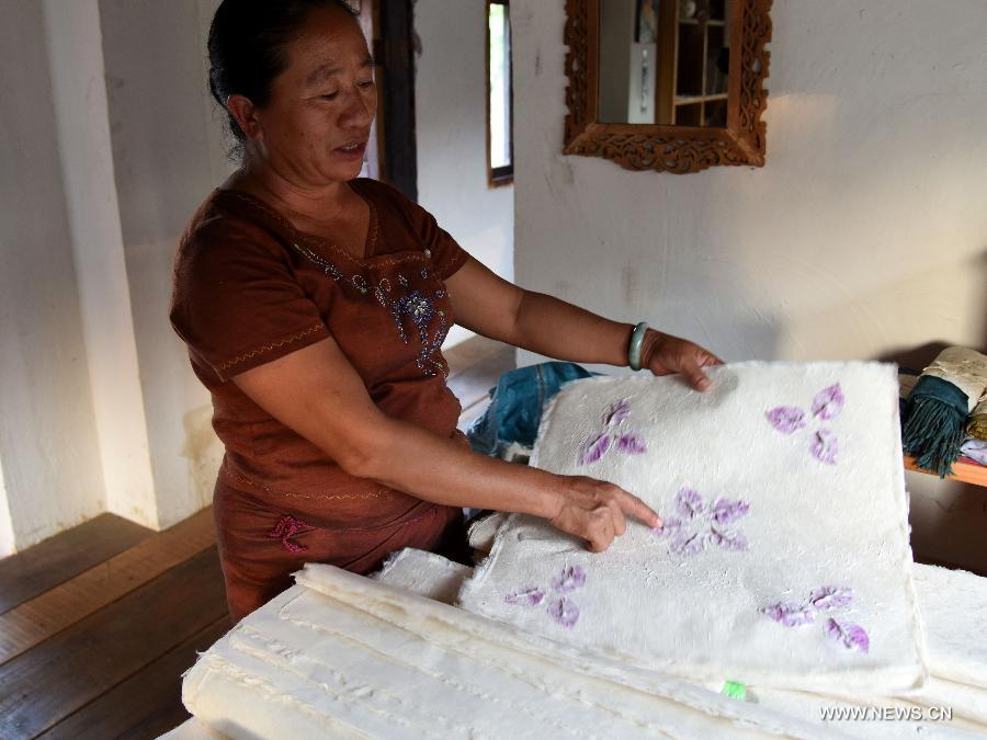 A woman displays hand-made mulberry bark paper in Mangtuan Village of Gengma Dai and Wa Autonomous County, southwest China's Yunnan Province, Oct. 15, 2015. The time-honored Dai people's paper-making skill, with a history of several centuries, is mainly mastered by local women and was listed as a national intangible cultural heritage in 2006. Local villagers see it as a key money spinner. [Xinhua]