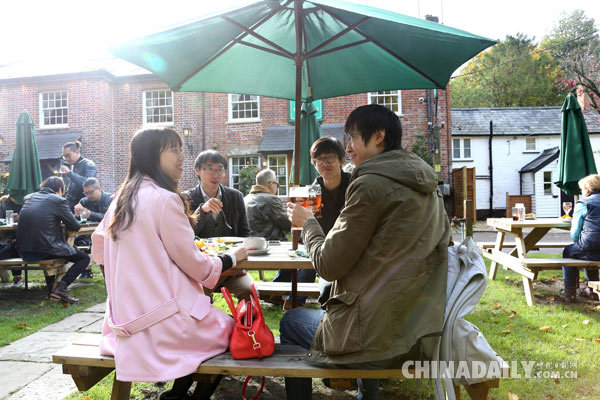 Chinese travelers drink outside the Plough at Cadsden pub. The place immediately became a hot tourist attraction after Xi's visit and it was so popular that tables inside were booked all weekend. [Photo/China Daily]