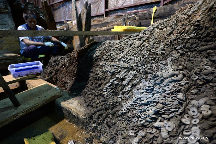 Photo taken on Aug. 4, 2015 shows an archaeologist clearing Wuzhu coins, the common currency in wide circulation during the West Han Dynasty (206 B.C.--25 A.D.), at the excavation site of royal tombs of Marquis of Haihun State, which date back to over 2,000 years ago, in Nanchang, capital of east China's Jiangxi Province.[Photo/Xinhua]