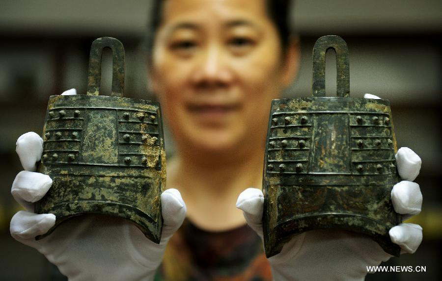 Photo taken on Aug. 6, 2015 shows an archaeologist displaying cultural relics unearthed from the excavation site of royal tombs of Marquis of Haihun State during the West Han Dynasty (206 B.C.--25 A.D.) in Nanchang, capital of east China's Jiangxi Province. [Photo/Xinhua]