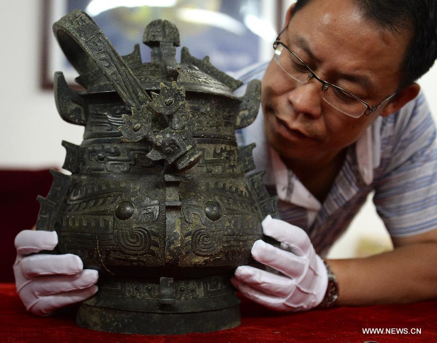 Photo taken on Aug. 6, 2015 shows an archaeologist studying on a bronze ware unearthed from the excavation site of royal tombs of Marquis of Haihun State during the West Han Dynasty (206 B.C.--25 A.D.) in Nanchang, capital of east China's Jiangxi Province.[Photo/Xinhua]