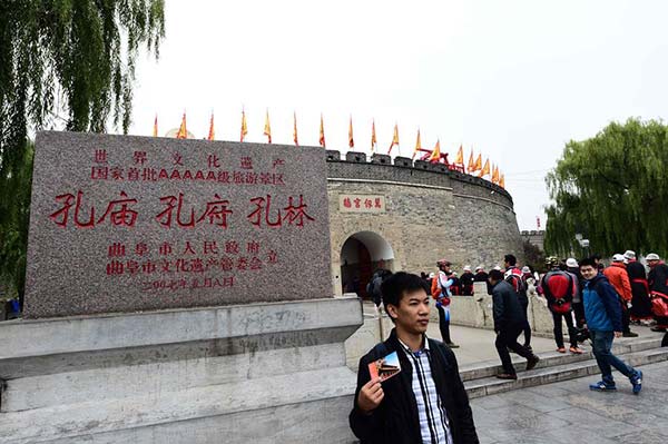 A visitor poses for a photo in front of Temple and Cemetery of Confucius and the Kong Family Mansion in Qufu. [Photo/Xinhua]