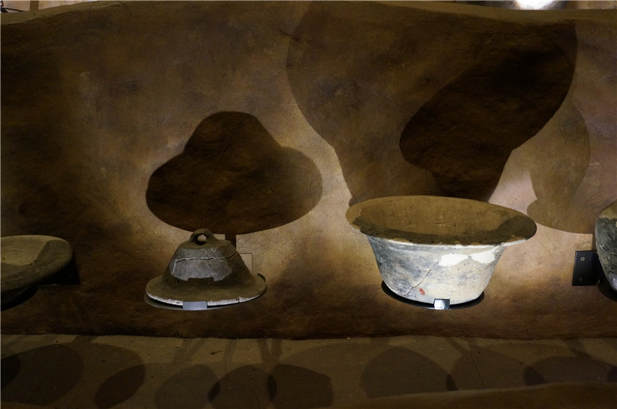 Potteries in Hemudu Site Museum casting beautiful shadows on walls. [Photo by Ruan Fan/chinadaily.com.cn]