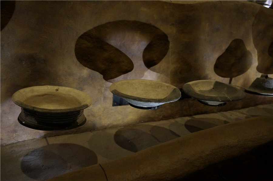 Potteries in Hemudu Site Museum casting beautiful shadows on walls. [Photo by Ruan Fan/chinadaily.com.cn]