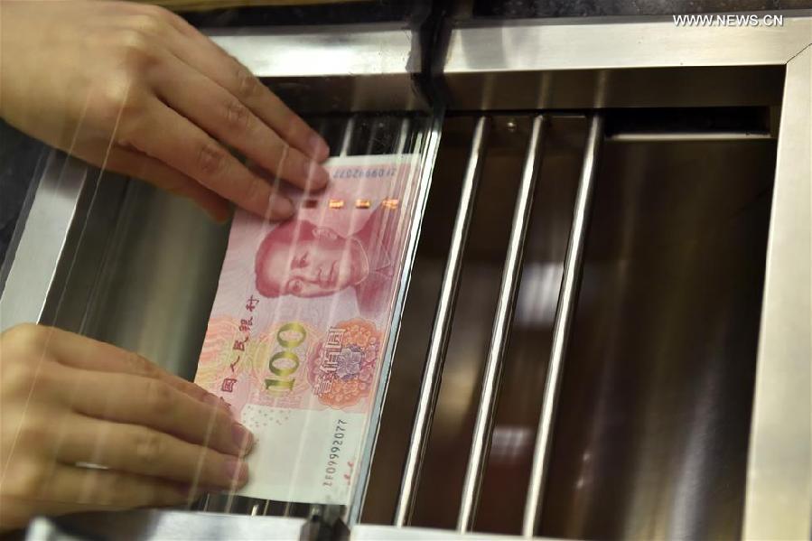 A bank staff member presents a new 100-yuan banknote to a resident at the Beijing Branch of the Bank of Communication in Beijing, capital of China. China's central bank released a new 100-yuan banknote on Thursday. The design stays largely the same as its former series, but the new banknotes are harder to conterfeit and easier for machines to read. The 100-yuan note is the largest denomination of the Chinese currency. [Xinhua]