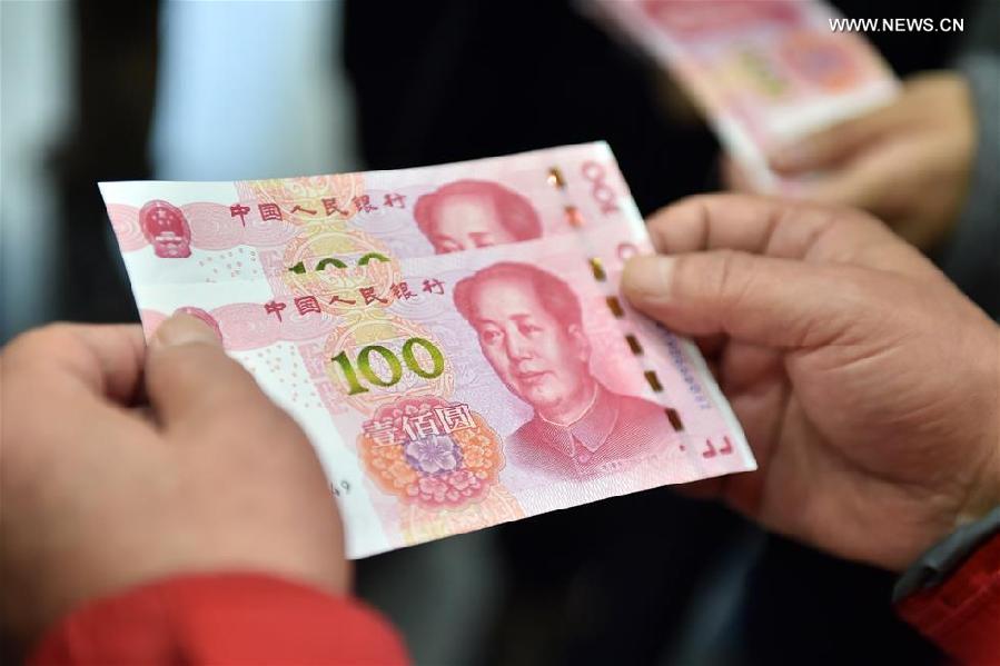 Residents hold two new 100-yuan banknotes withdrawn from the Beijing Branch of the Bank of Communication in Beijing, capital of China. China's central bank released a new 100-yuan banknote on Thursday. The design stays largely the same as its former series, but the new banknotes are harder to conterfeit and easier for machines to read. The 100-yuan note is the largest denomination of the Chinese currency. [Xinhua]