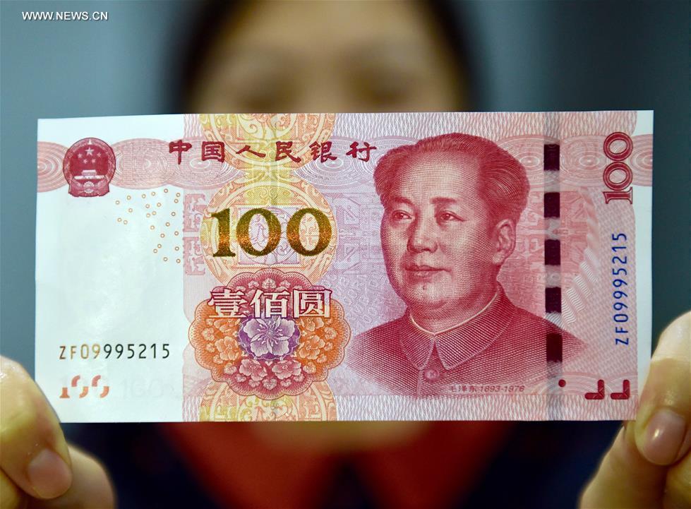 A resident displays a new 100-yuan banknote in Beijing, capital of China, Nov. 12, 2015. China's central bank released a new 100-yuan banknote on Thursday. The design stays largely the same as its former series, but the new banknotes are harder to conterfeit and easier for machines to read. The 100-yuan note is the largest denomination of the Chinese currency. [Xinhua]