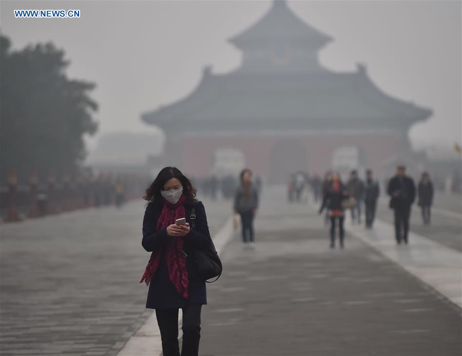 A woman wearing a mask walks amid heavy fog at the Temple of Heaven Park in Beijing, capital of China, Nov. 12, 2015. Beijing Meteorological Bureau has issued a yellow alert for heavy fog on Thursday, and the pollution is expected to extend to Saturday. [Xinhua]