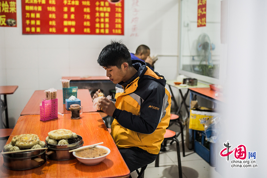 Hou has breakfast on his way to work. [Photo by Zheng Liang/China.org.cn]