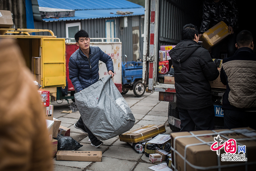 Hou loads the goods onto his electric motorcycle after compiling an inventory. [Photo by Zheng Liang/China.org.cn] 