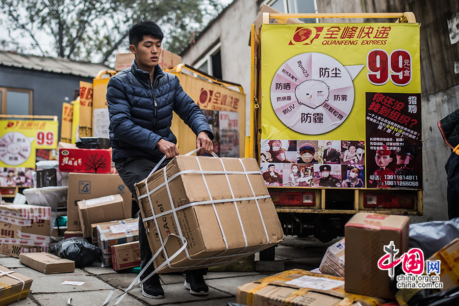 Hou loads the goods onto his electric motorcycle after making an inventory of them. [Photo by Zheng Liang/China.org.cn]