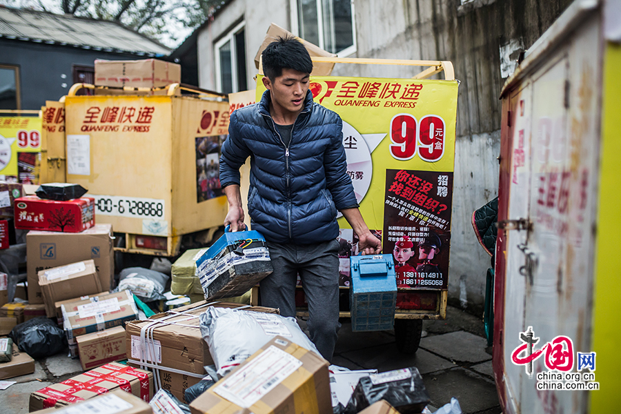 Hou installs the batteries for his electric motorcycle before starting off on the day's delivery round. [Photo by Zheng Liang/China.org.cn]