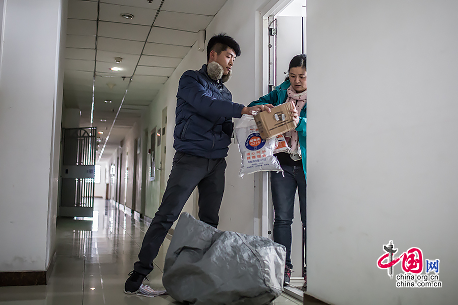 Hou arrives at his second destination of the day, an office building where he has to deliver the goods to the door. [Photo by Zheng Liang/China.org.cn]