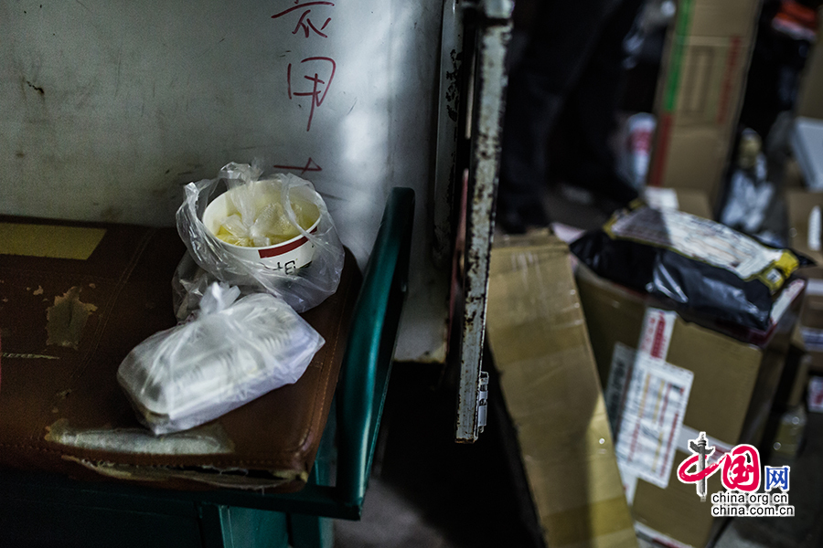 The porridge and fried noodles on the motorcycle seat are already cold while Hou is still busy organizing the goods for delivery. He won't have his supper until everything is done. [Photo by Zheng Liang/China.org.cn]