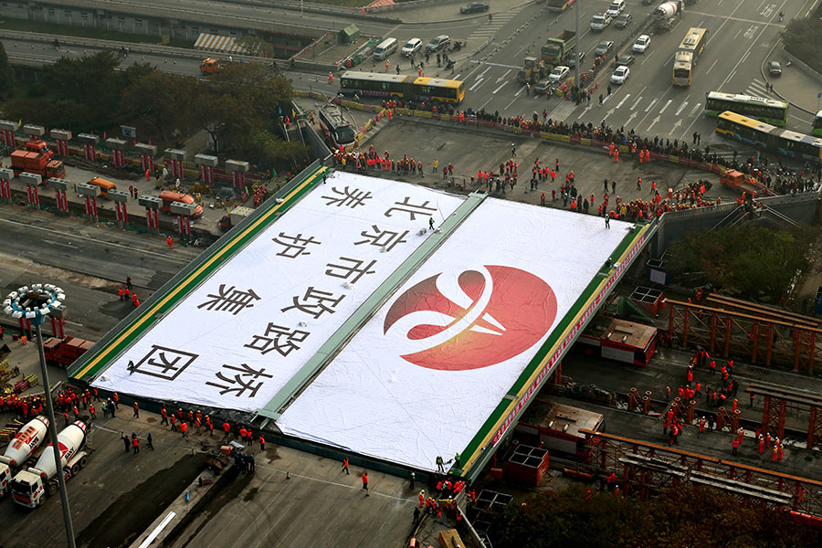 New bridge sections are moved slowly into position at Beijing's Sanyuanqiao junction on the 3rd Ring Road on Sunday. Replacement of the decaying bridge took only about 36 hours. Workers used global positioning systems, lasers and robots to replace old sections with prefabricated steel structures. Traffic flow resumed late on Sunday afternoon. [Photo/China Daily]