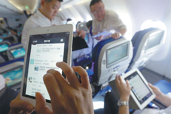 Passengers use WiFi services to surf Internet on mobile gadgets on a flight of China Eastern Airlines. [Photo by Liu Xin / For China Daily] 