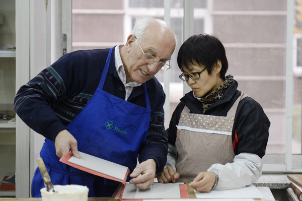 Friedbert Ewertz, a monk from Germany, demonstrates how to bind gospel books.[Photo by Wei Xiaohao/China Daily] 