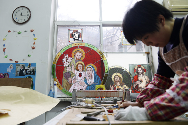 A nun makes stained glass decorations in the seminary's art department. [Photo by Wei Xiaohao/China Daily] 