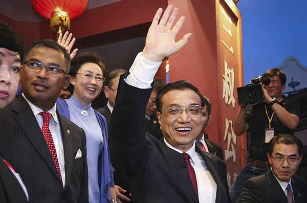 Premier Li Keqiang and his wife Cheng Hong greet the public in front of a store selling specialized products during the couple's visit to Malacca on Sunday. [Photo/Xinhua]