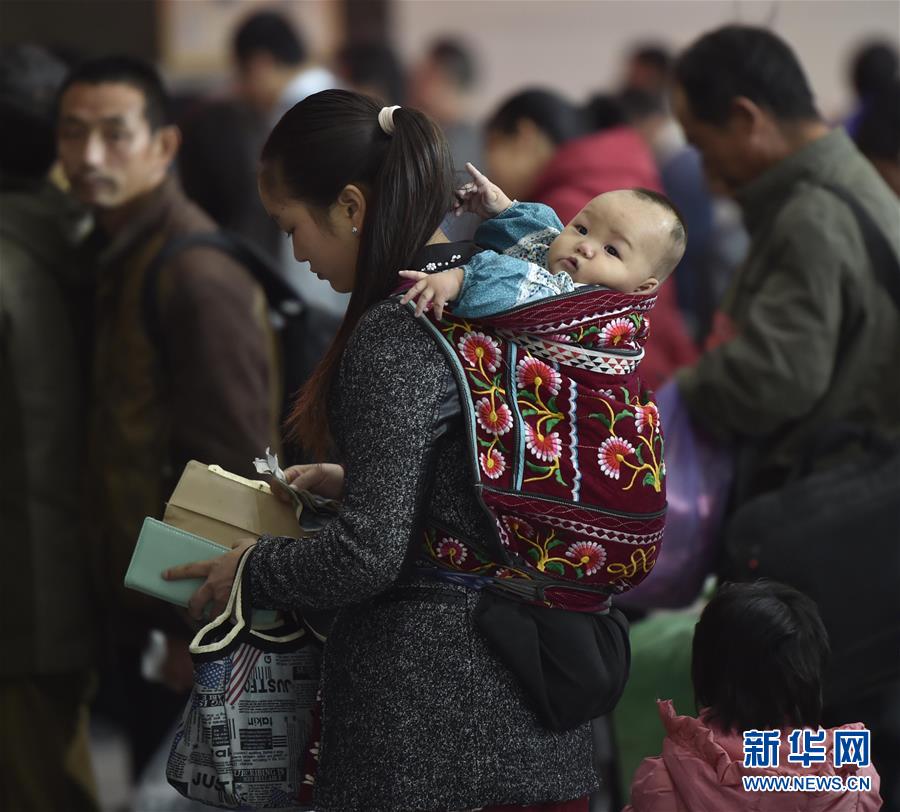 A woman carrying her baby waits in line to buy a ticket at Fuzhou Railway Station, East China&apos;s Fujian province on Nov 28, 2015. Railways began selling tickets on Thursday for trains scheduled to leave between Jan 24 to March 3, a 40-day period in China known as &apos;Chunyun&apos; when people travel back home to celebrate the Spring Festival, which falls on Feb 8 in 2016.