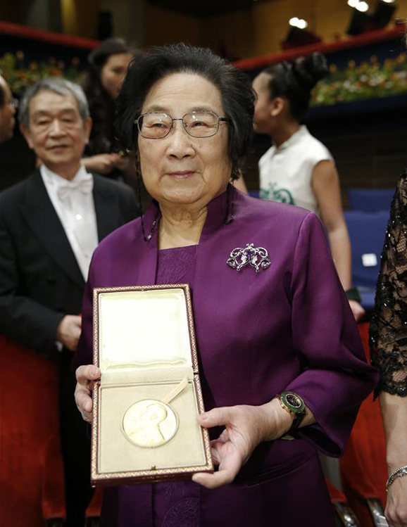 2015's Nobel laureate in Physiology or Medicine Tu Youyou (L) shows her medal following the Nobel Prize award ceremony at the Concert Hall in Stockholm, capital of Sweden, Dec. 10, 2015. [Photo/Xinhua]