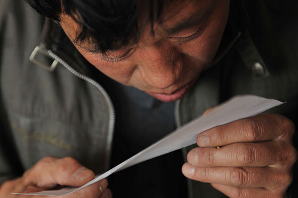Wu Zhicheng, a Beijing resident who has no hukou, checks a paper that may help him reinstate his household registration in January. Wu said he lost his hukou 43 years ago because of a mistake that occurred when the local police relocated it to his employer. [Photo by Wu Jiang/for China Daily]