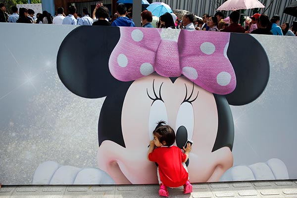 A girl touches a Minnie Mouse cartoon at the Disney's flagship store in Shanghai. [China Daily]
