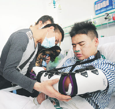 Tian Zeming (right), being tended to by his father on Thursday, is recovering at Guangming New District Hospital in Shenzhen. Tian was rescued from beneath debris on Wednesday, 67 hours after Sunday's deadly landslide. Xuan Hui / for China Daily