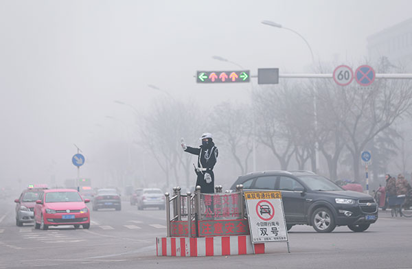 A police traffic officer wears a mask at a crossroads in Baoding, Hebei province, on Dec 25. Lingering smog prompted local authorities to launch a month-long pollution red alert in the city. [Photo/China Daily]