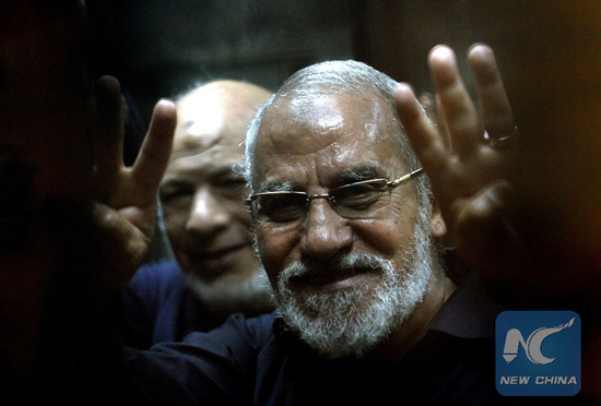 A file picture taken on May 8, 2014 shows Egyptian Brotherhood's supreme guide Mohamed Badie flashing the 'Rabaa' sign, which means four in Arabic, remembering those killed in the crackdown on the Rabaa al-Adawiya protest camp in Cairo last year, during his trial at a police academy in Cairo. [Photo/Xinhua]