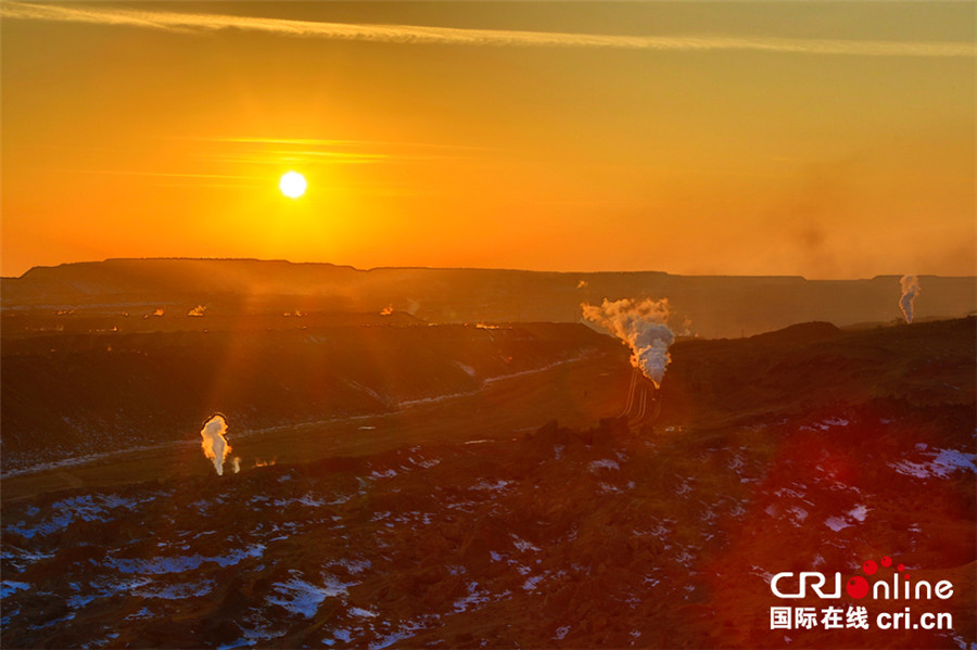 Steam trains cross the opencast coal mine in the sunlight at Sandaoling in Hami prefecture, Northwest China's Xinjiang Uygur Autonomous Region, Jan 13, 2016. [Photo/cri.cn]