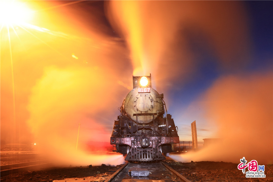 A steam train crosses the opencast coal mine at Sandaoling in Hami prefecture, Northwest China's Xinjiang Uygur Autonomous Region, Jan 13, 2016. [Photo/China.org.cn]