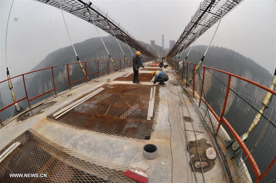 Laborers work on the glass bridge across the Zhangjiajie Grand Canyon in Zhangjiajie, central China's Hunan Province, Jan. 18, 2016. The bridge is 430 meters long, six meters wide and 300 meters above the valley. It is capable of holding 800 people at once and is expected to be opened to tourists in the first half of this year. [Xinhua]