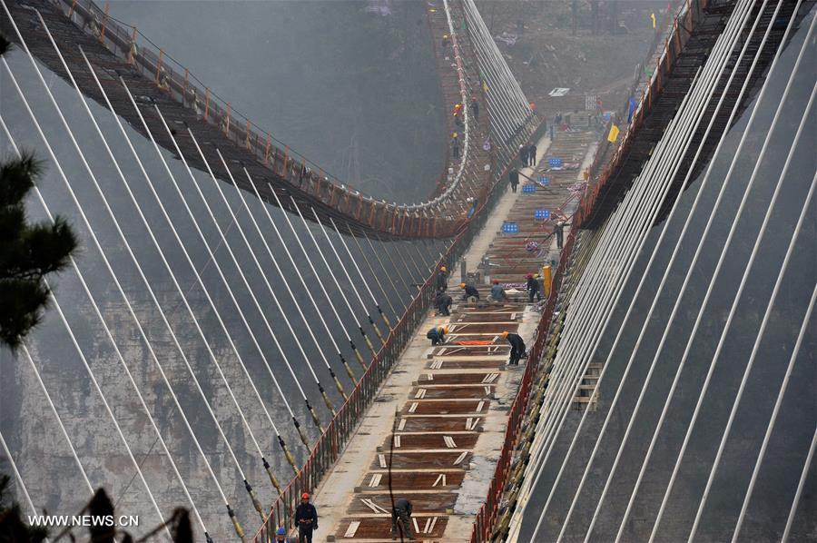 Laborers work on the glass bridge across the Zhangjiajie Grand Canyon in Zhangjiajie, central China's Hunan Province, Jan. 18, 2016. The bridge is 430 meters long, six meters wide and 300 meters above the valley. It is capable of holding 800 people at once and is expected to be opened to tourists in the first half of this year. [Xinhua]