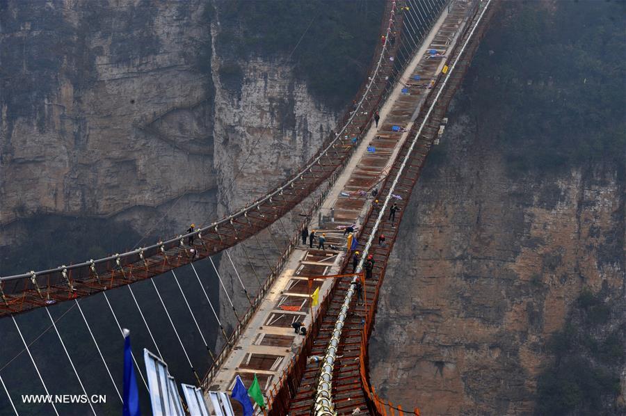 Laborers work on the glass bridge across the Zhangjiajie Grand Canyon in Zhangjiajie, central China's Hunan Province, Jan. 18, 2016. The bridge is 430 meters long, six meters wide and 300 meters above the valley. It is capable of holding 800 people at once and is expected to be opened to tourists in the first half of this year. [Xinhua]