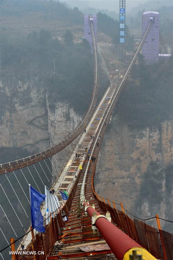 Laborers work on the glass bridge across the Zhangjiajie Grand Canyon in Zhangjiajie, central China's Hunan Province, Jan. 18, 2016. The bridge is 430 meters long, six meters wide and 300 meters above the valley. It is capable of holding 800 people at once and is expected to be opened to tourists in the first half of this year. [Xinhua]