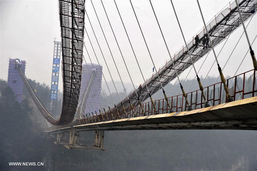 Photo taken on Jan. 18, 2016 shows the glass bridge across the Zhangjiajie Grand Canyon under construction in Zhangjiajie, central China's Hunan Province, Jan. 18, 2016. The bridge is 430 meters long, six meters wide and 300 meters above the valley. It is capable of holding 800 people at once and is expected to be opened to tourists in the first half of this year. [Xinhua]