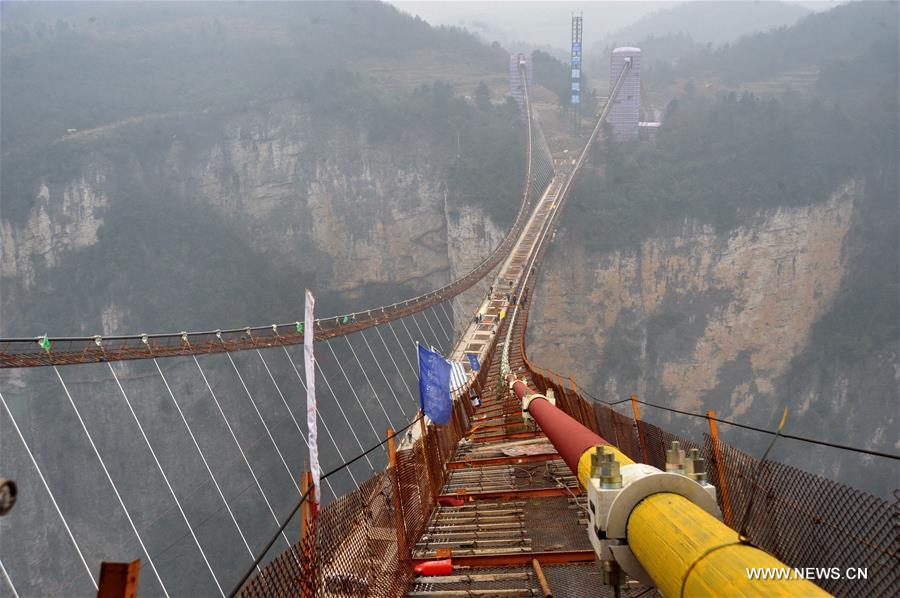 Photo taken on Jan. 18, 2016 shows the glass bridge across the Zhangjiajie Grand Canyon under construction in Zhangjiajie, central China's Hunan Province, Jan. 18, 2016. The bridge is 430 meters long, six meters wide and 300 meters above the valley. It is capable of holding 800 people at once and is expected to be opened to tourists in the first half of this year. [Xinhua]